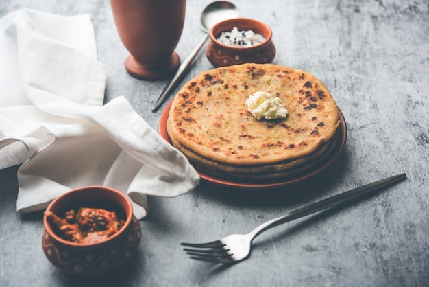 Aloo Paratha 또는 인도 감자 속을 채운 플랫브레드 위에 버터를 얹습니다. 신선하고 달콤한 라씨, 처트니, 피클과 함께 제공됩니다. 선택적 초점