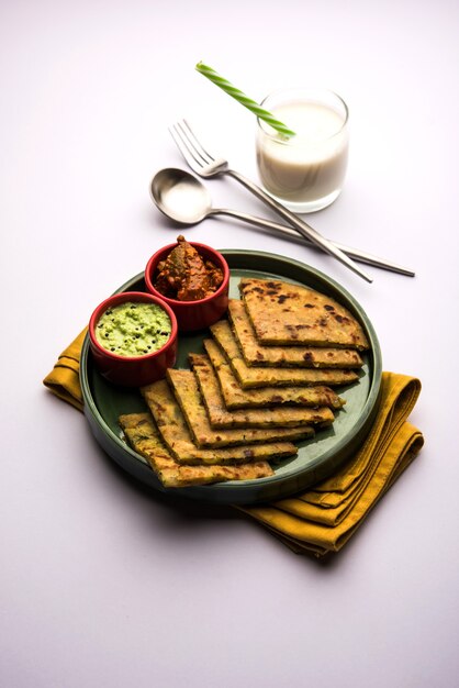 Aloo Paratha or Indian Potato stuffed Flatbread with butter on top. Served with fresh sweet Lassi, chutney and pickle . selective focus