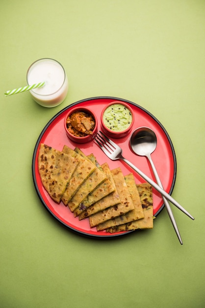 Aloo Paratha or Indian Potato stuffed Flatbread with butter on top. Served with fresh sweet Lassi, chutney and pickle . selective focus