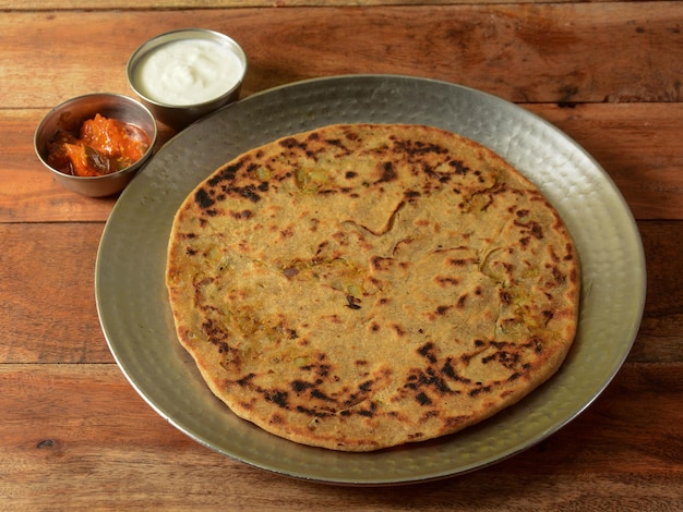 Aloo Paratha of Indiase Aardappel gevulde Flatbread Geserveerd met verse wrongel en augurk geïsoleerd over een rustieke houten achtergrond selectieve aandacht