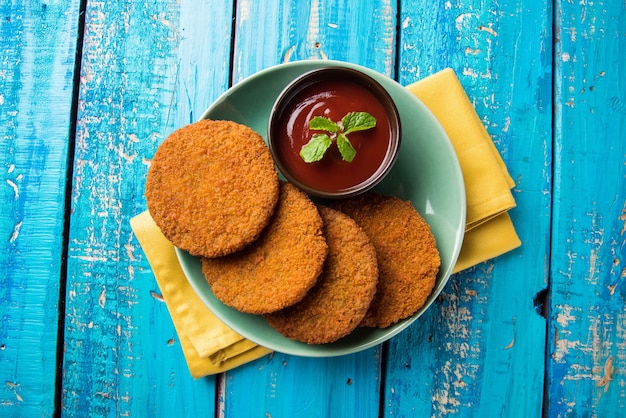 Aloo Tikki of Patties of Cutlet is een populaire snack of snack uit India, geserveerd met Tomatenketchup of Imli-chutney op een humeurige achtergrond. Selectieve focus