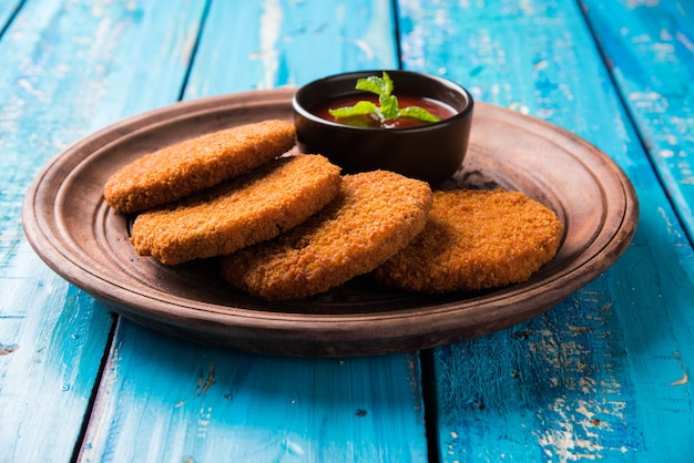 Aloo Tikki of Patties of Cutlet is een populaire snack of snack uit India, geserveerd met Tomatenketchup of Imli-chutney op een humeurige achtergrond. Selectieve focus