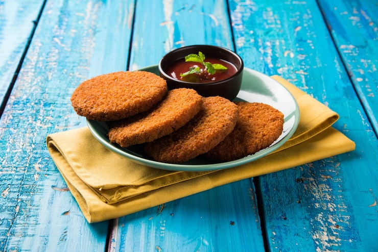फोटो aloo tikki or patties or cutlet is a popular snack or snack from india, served with tomato ketchup or imli chutney over moody background. selective focus