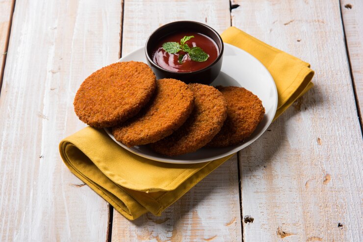 फोटो aloo tikki or patties or cutlet is a popular snack or snack from india, served with tomato ketchup or imli chutney over moody background. selective focus