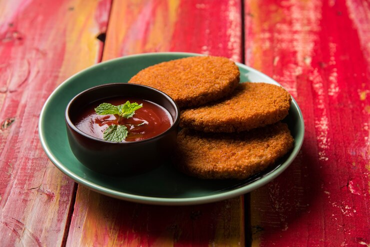 फोटो aloo tikki or patties or cutlet is a popular snack or snack from india, served with tomato ketchup or imli chutney over moody background. selective focus