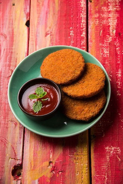 Aloo Tikki or Patties or Cutlet is a popular snack or snack from India, Served with Tomato Ketchup or Imli chutney over moody background. Selective focus