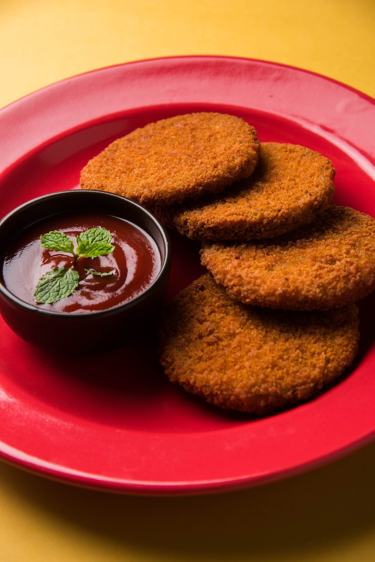 फोटो aloo tikki or patties or cutlet is a popular snack or snack from india, served with tomato ketchup or imli chutney over moody background. selective focus