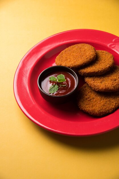 Aloo Tikki or Patties or Cutlet is a popular snack or snack from India, Served with Tomato Ketchup or Imli chutney over moody background. Selective focus