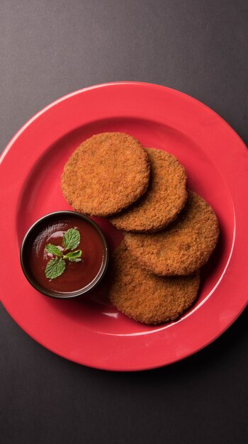 Aloo Tikki 또는 Patties 또는 Cutlet은 변덕스러운 배경 위에 토마토 케첩 또는 Imli 처트니와 함께 제공되는 인도의 인기 있는 스낵 또는 스낵입니다. 선택적 초점