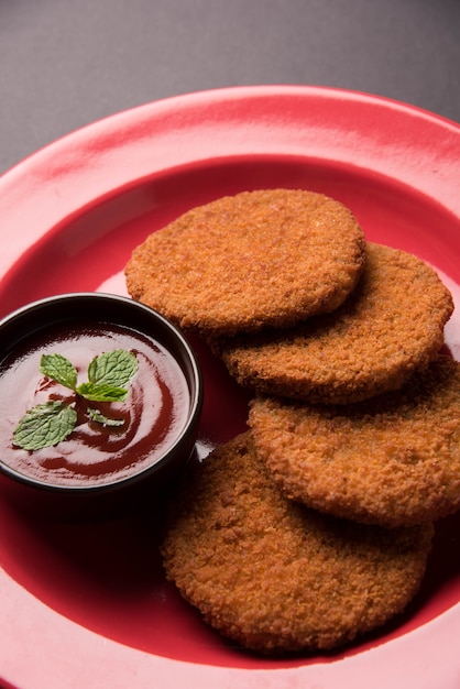 Aloo Tikki 또는 Patties 또는 Cutlet은 변덕스러운 배경 위에 토마토 케첩 또는 Imli 처트니와 함께 제공되는 인도의 인기 있는 스낵 또는 스낵입니다. 선택적 초점