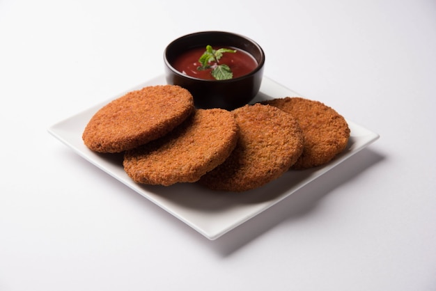 Aloo Tikki or Patties or Cutlet is a popular snack or snack from India, Served with Tomato Ketchup or Imli chutney over moody background. Selective focus