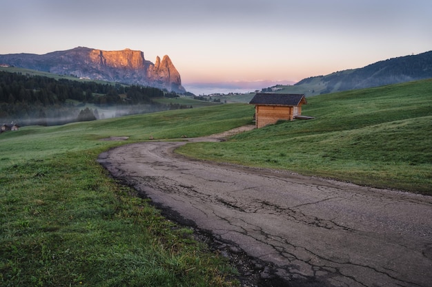 Alpe di Siusi 또는 Seiser Alm 산길과 Sciar 또는 Schlern 산은 일출의 밝은 Dolomites에 있습니다.