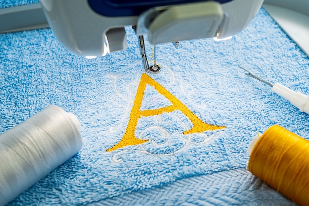 Photo alphabet logo design on towel in hoop of embroidery machine