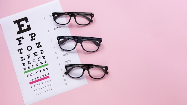 Alphabet table with glasses on pink background