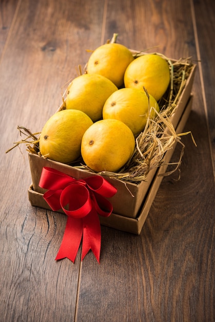 Alphonso-mango's in een geschenkdoos over gras en vastgebonden met rood lint, selectieve focus