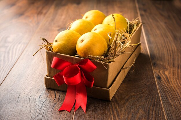 Alphonso-mango's in een geschenkdoos over gras en vastgebonden met rood lint, selectieve focus