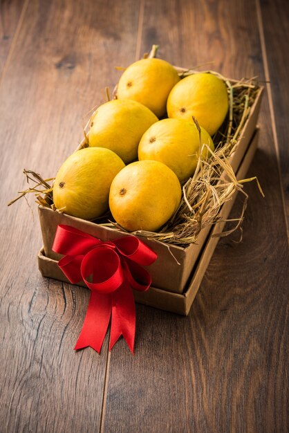 Alphonso mangoes in a gift box over grass and tied with red ribbon, selective focus