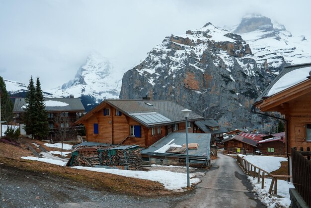 Альпийская горная деревня с заснеженными крышами и кучей дров в швейцарских Альпах