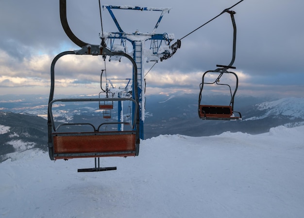 Фото Горнолыжный подъемник с местами для катания на лыжах на закате в очень ветреную погоду