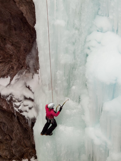 Alpinist ascenting a frozen waterfall in Ice park, Ouray.