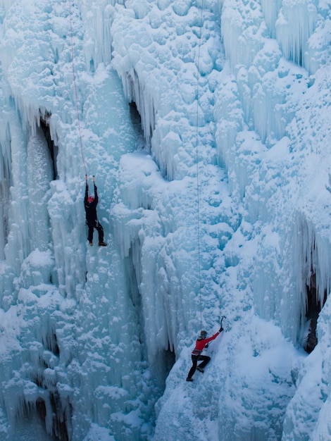 Alpinist ascenting a frozen waterfall in Ice park, Ouray.