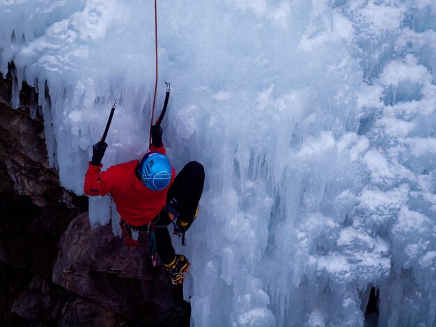 Alpinist die een bevroren waterval beklimt in Ice park, Ouray.