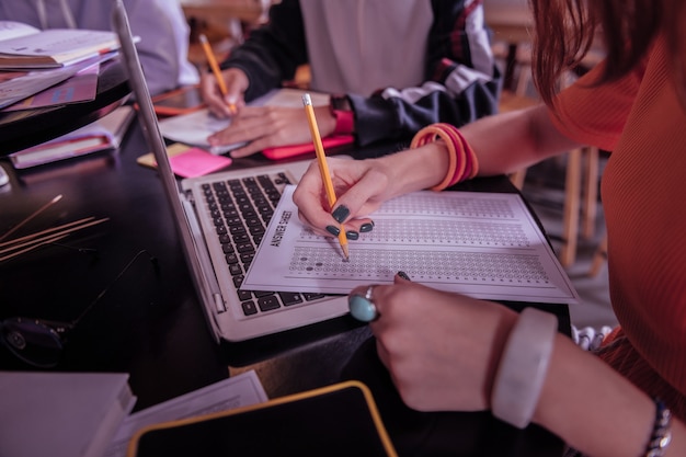 Già fatto. attenta giovane donna seduta al suo posto di lavoro mentre controlla il suo compito