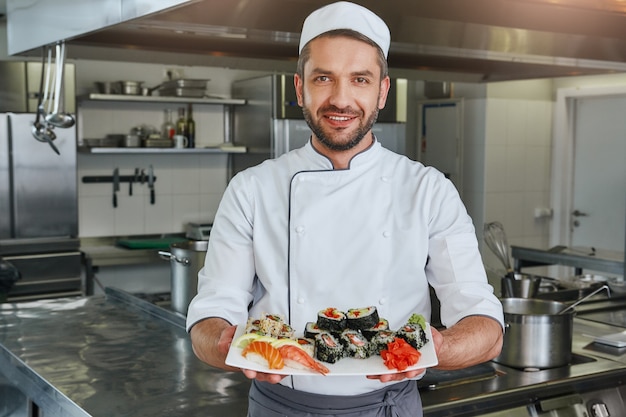 Already ready portrait of cheerful chef standing with cooked traditional japanese sushi