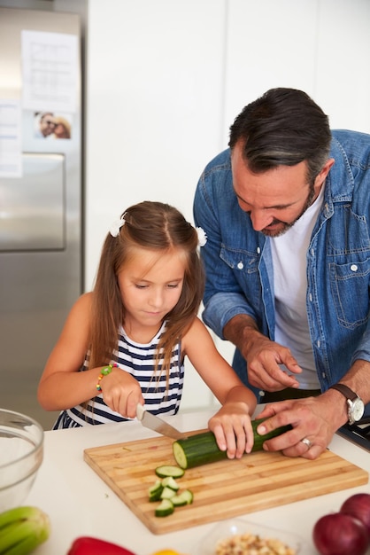 Als een professionele chef-kok al Shot van een schattig klein meisje dat thuis kookt met haar vader