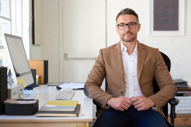 Als je innovatie nodig hebt, vertrouw je Portret van een positieve, volwassen creatieve professional aan zijn bureau