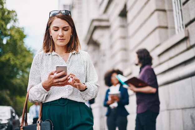 Als u onderweg verbonden bent, mist u nooit kansen. Shot van een zakenvrouw die haar mobiele telefoon gebruikt terwijl ze in de stad is