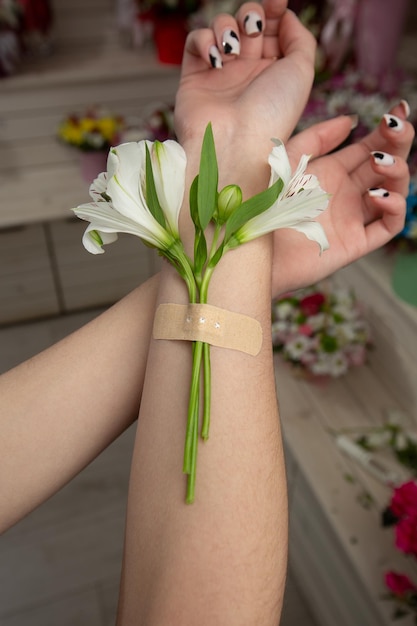 Alstroemeria bevestigd aan een hand met gipsbanden Natuurlijke frisheid en vrouwenhand Handencosmetica met witte bloemplakpleister