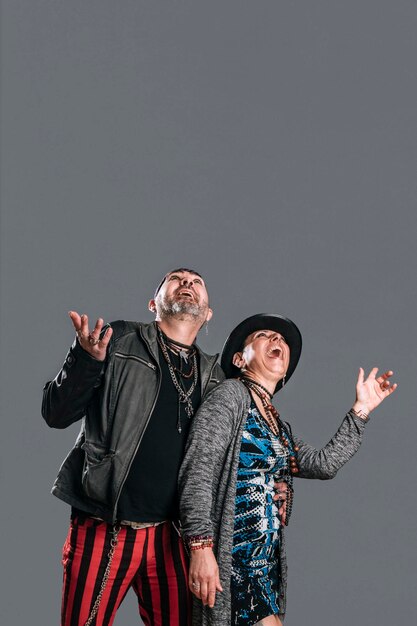 Alternately dressed male and female couple look up surprised in study shot on gray background