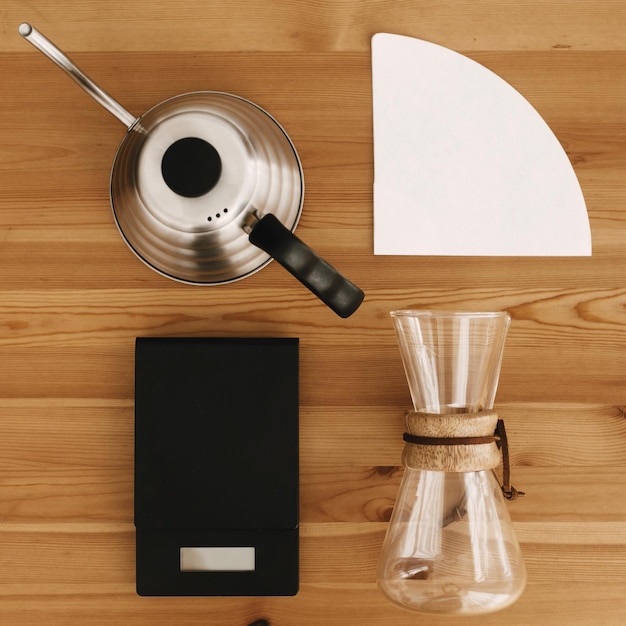 Foto alternatieve methode voor het zetten van koffie plat leggen stijlvolle accessoires en items voor alternatieve koffie op houten tafel stalen ketel elektronische weegschaal filter en glazen kolf bovenaanzicht