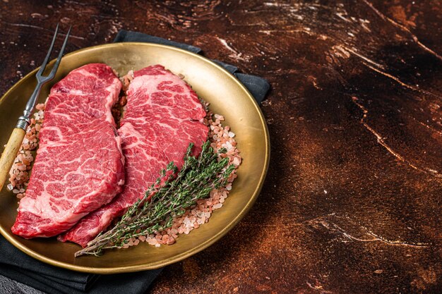 Alternative beef steak Denver raw meat steak with herbs Dark background Top view Copy space