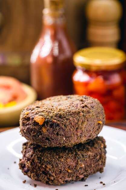 Alternative burger made from black beans, vegetables, carrots, seasonings, beets, wholemeal flour and quinoa, with various vegetables.