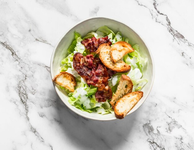 Alternative caesar salad with bacon on a light marble background top view Delicious brunch snack