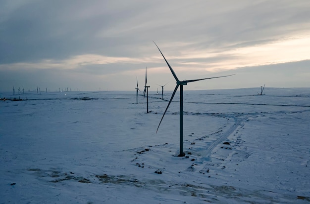 代替エネルギー源。環境にやさしい電気。冬のフレボランド青空のオランダの干拓地の雪に覆われた畑と風力タービン。上面図、空中写真、グリーンエネルギー