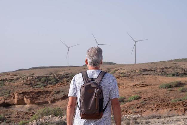 Alternative energy wind farm on the mountain in Tenerife Back view of mature man looking at wind turbines farm Concept of renewable energy love of nature clean green electricity future