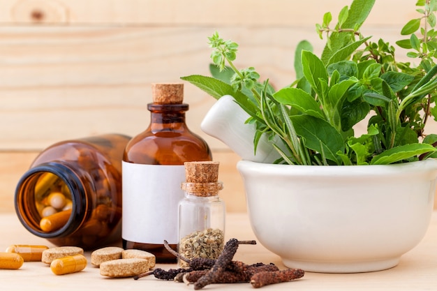 Alternative health care fresh herbs in white mortar on wooden background.