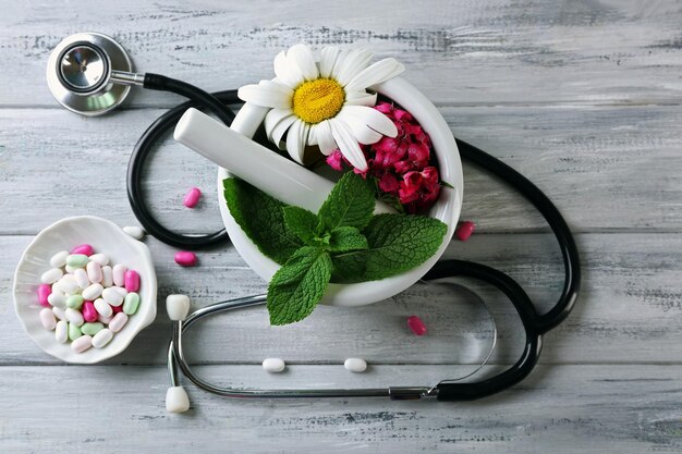 Alternative medicine herbs and stethoscope on wooden table background