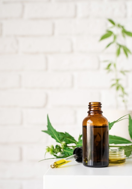 Medicina alternativa, cosmetici naturali. olio di cbd e foglie di cannabis cosmetici vista frontale, copia spazio, mock up design