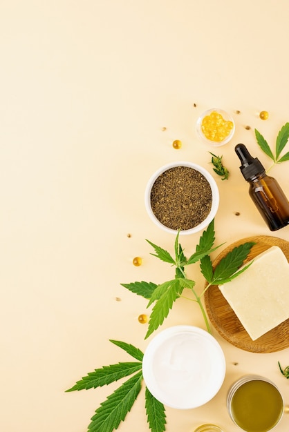 Alternative medicine, natural cosmetics. cbd oil and cannabis leaves cosmetics top view on orange background, flat lay