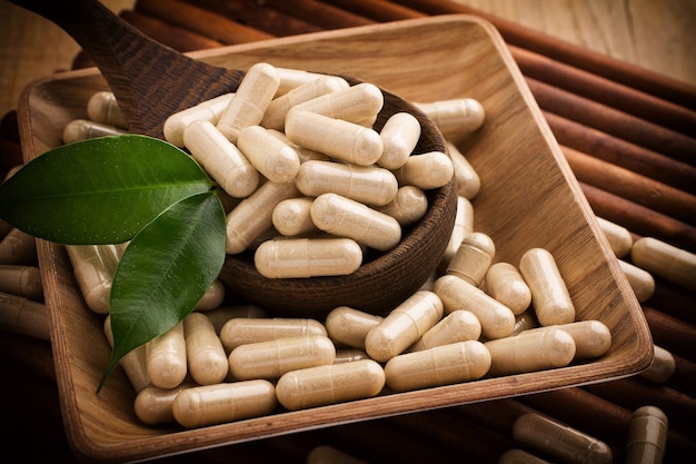 Alternative medicine tablets on a wooden spoon green leaf