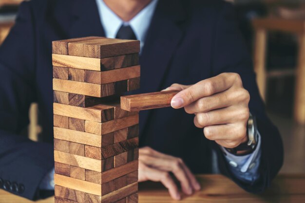 Photo alternative risk concept plan and strategy in business risk to make buiness growth concept with wooden blocks images of hand of businesspeople placing and pulling wood block on the tower