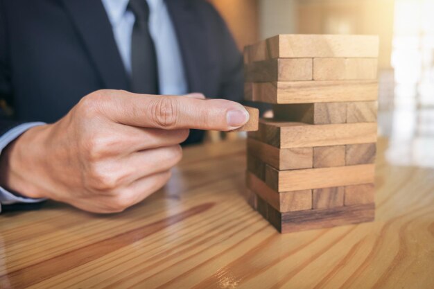 Photo alternative risk concept plan and strategy in business risk to make buiness growth concept with wooden blocks images of hand of businesspeople placing and pulling wood block on the tower