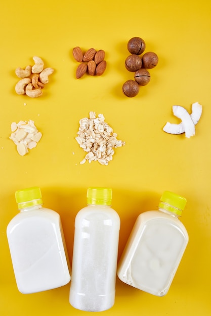 Alternative types of vegan milks in bottles on a yellow background