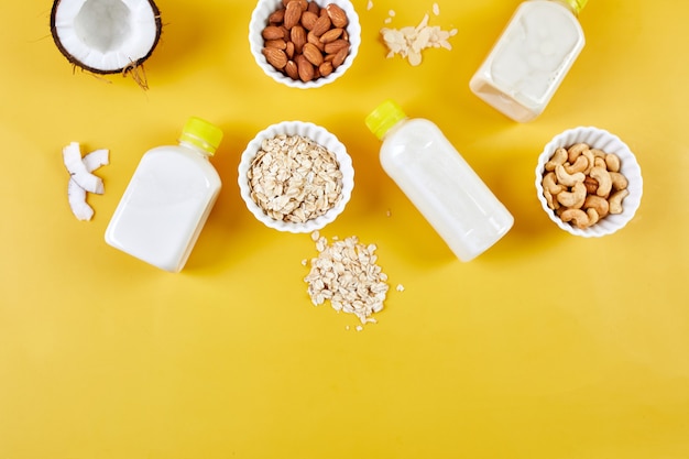 Alternative types of vegan milks in bottles on a yellow background