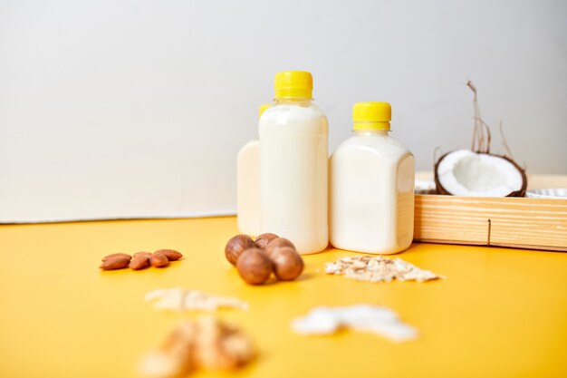 Alternative types of vegan milks in bottles on a yellow surface, Various vegan plant based milk and ingredients, non-dairy milk, alternative milk