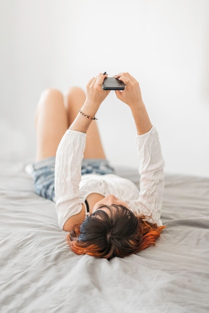 Фото Альтернативная молодая женщина с цветными волосами отдыхает дома и делает домашнее задание, улыбаясь и расслабляясь
